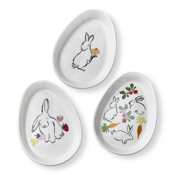 3 assorted white egg shaped plates with bunnies and flowers or fruits on them.
