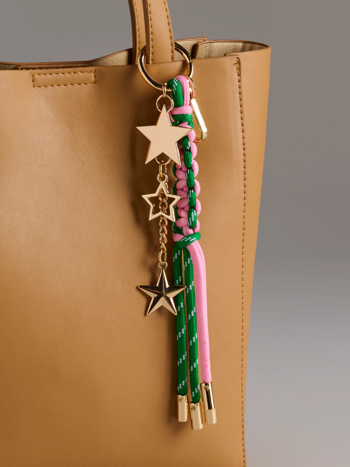 close-up of green Starlet Bag Charm hung on beige tote bag