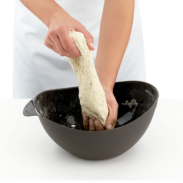 person kneading dough over a lekue bread makers.
