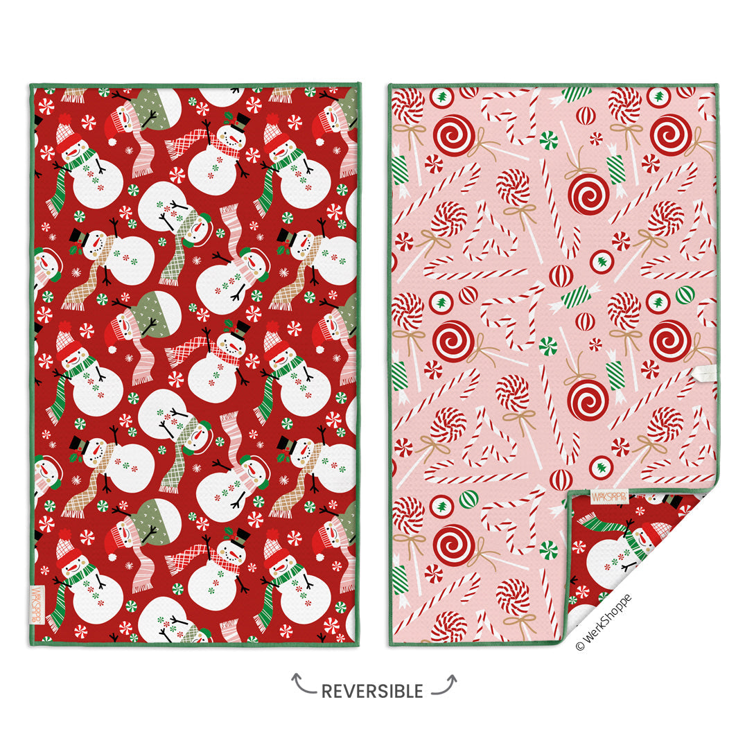 two sides of a reversible hand towel, one with snowmen on red and the other with candy cane patterns on pink.