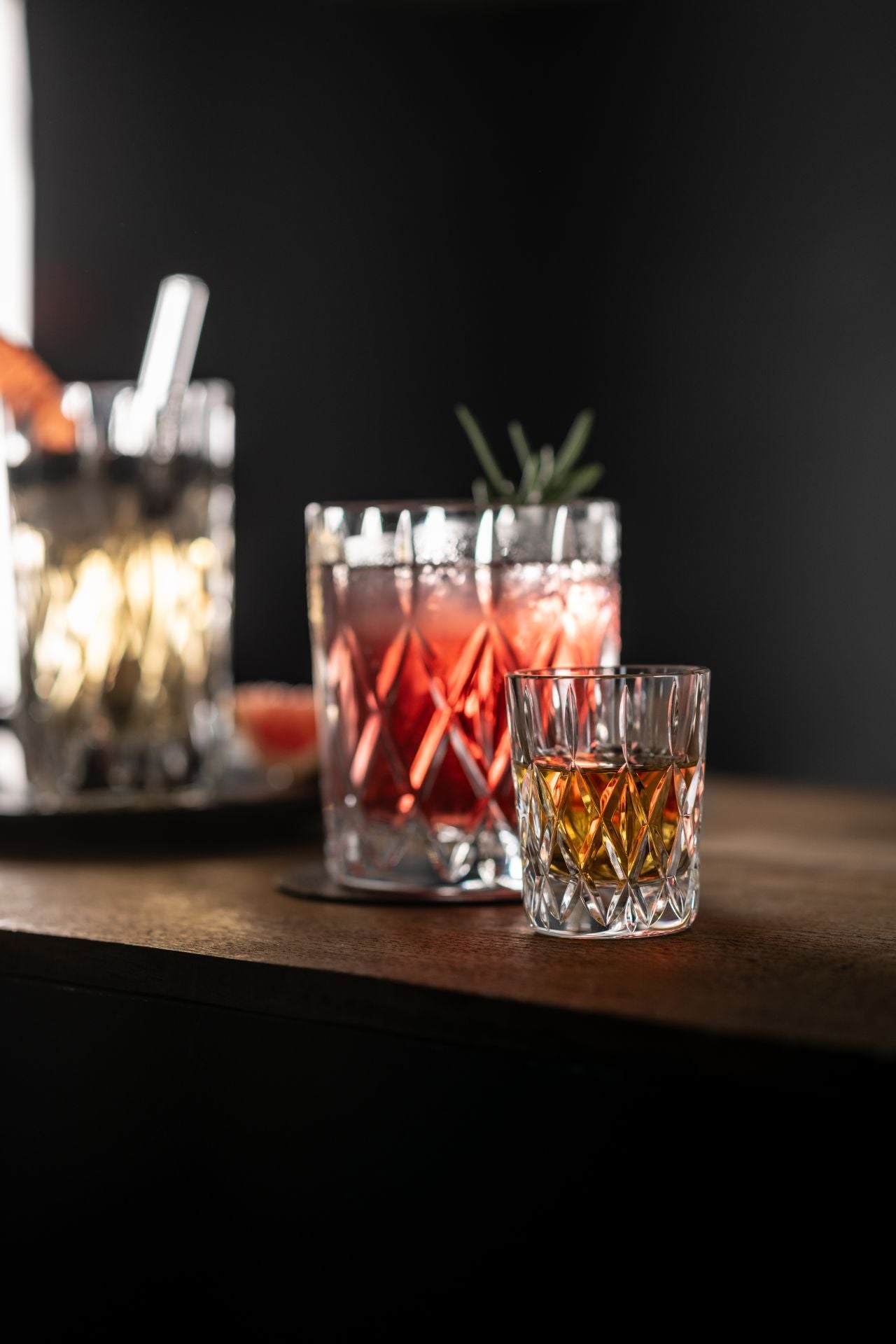 shot glass filled with liquid set on a wooden surface with other glasses