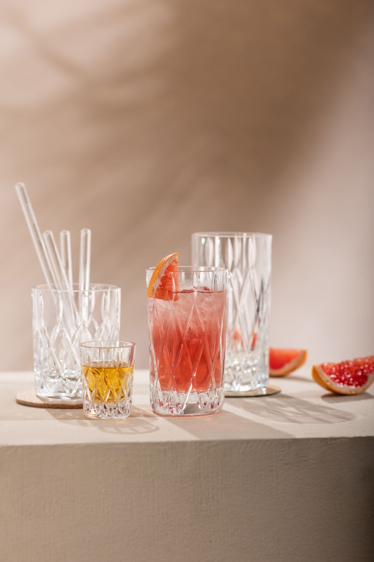 assorted glass drinking glasses arranged on a table, 2 glasses are filled with beverages