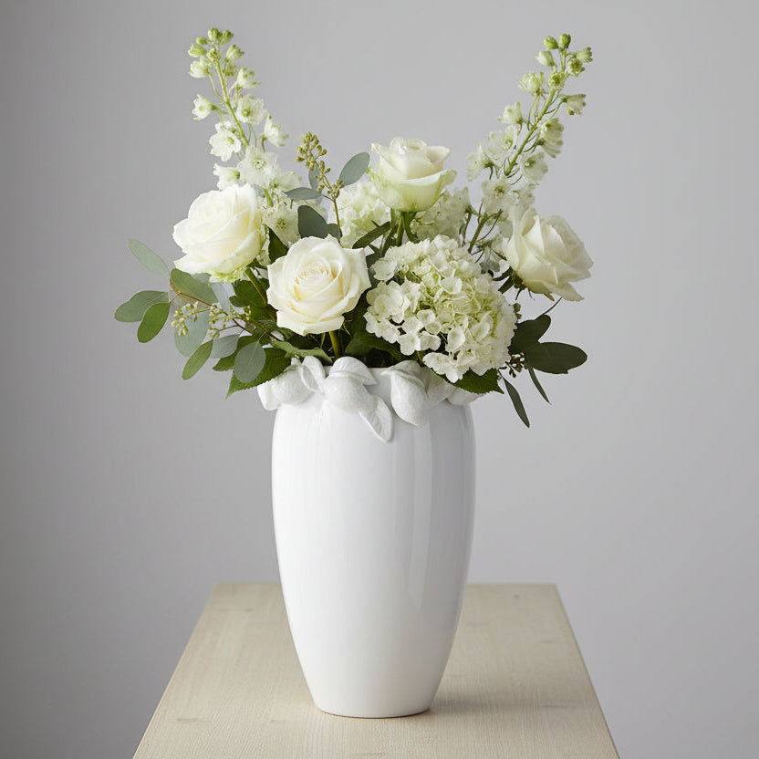 white vase with lemon design around the top rim filled with fresh white florals