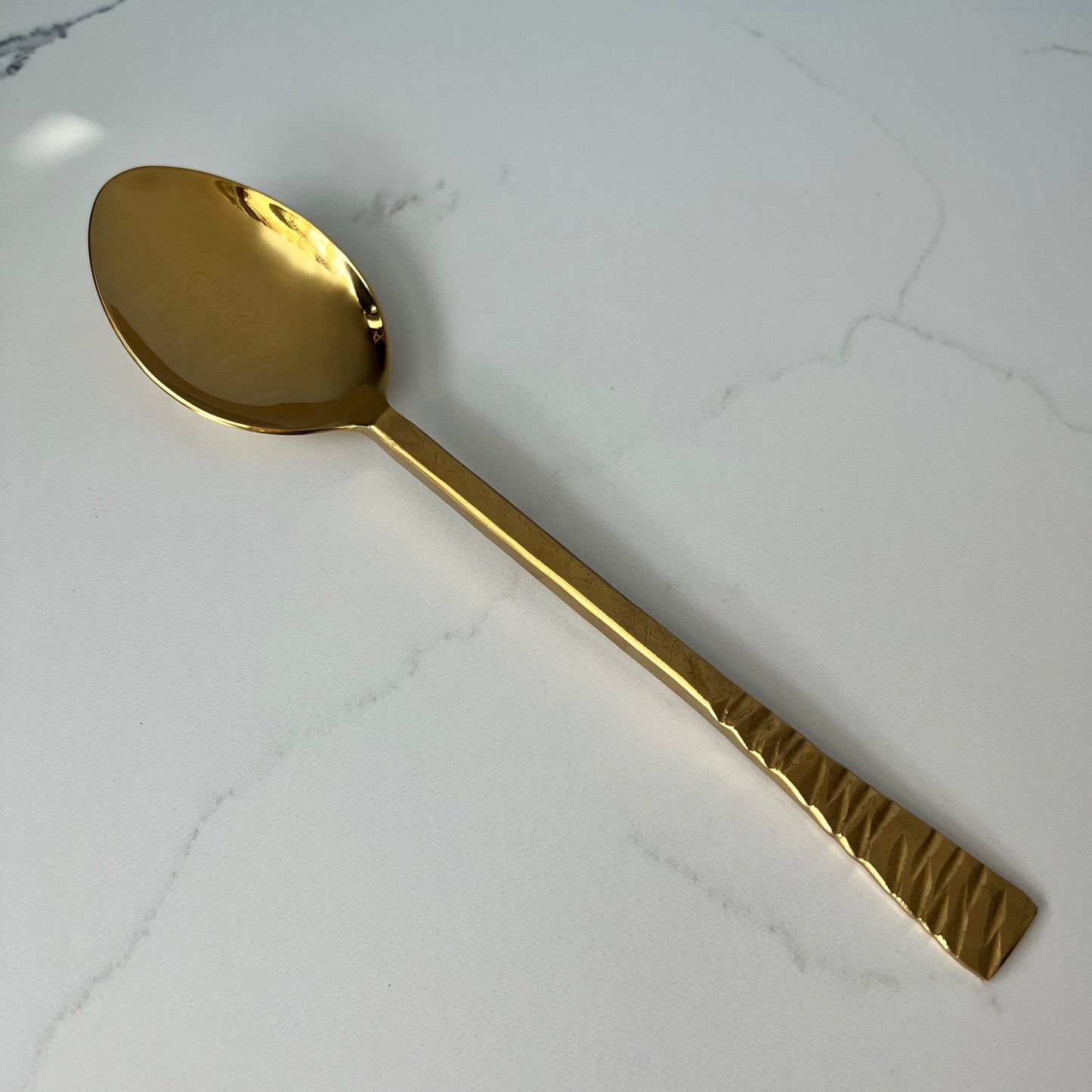 gold serving spoon on marble countertop.