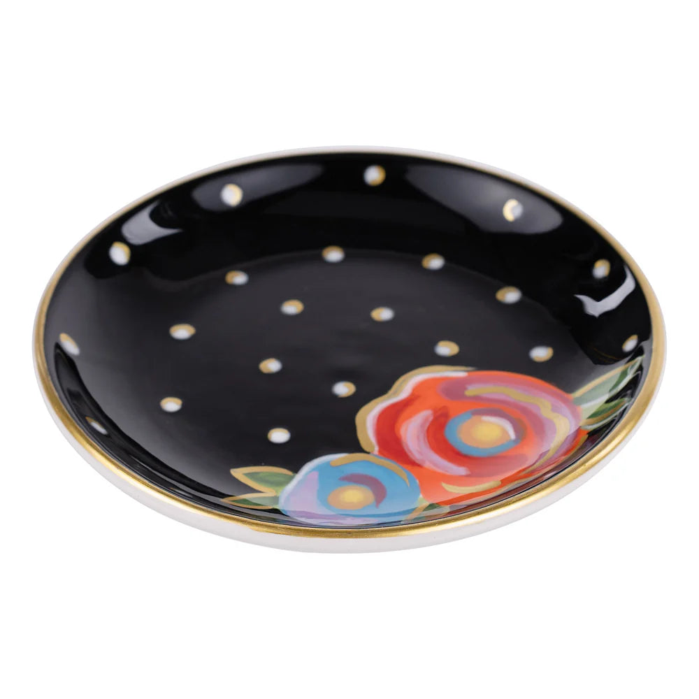 side view of Black ceramic plate with white dots and colorful floral designs on a white background