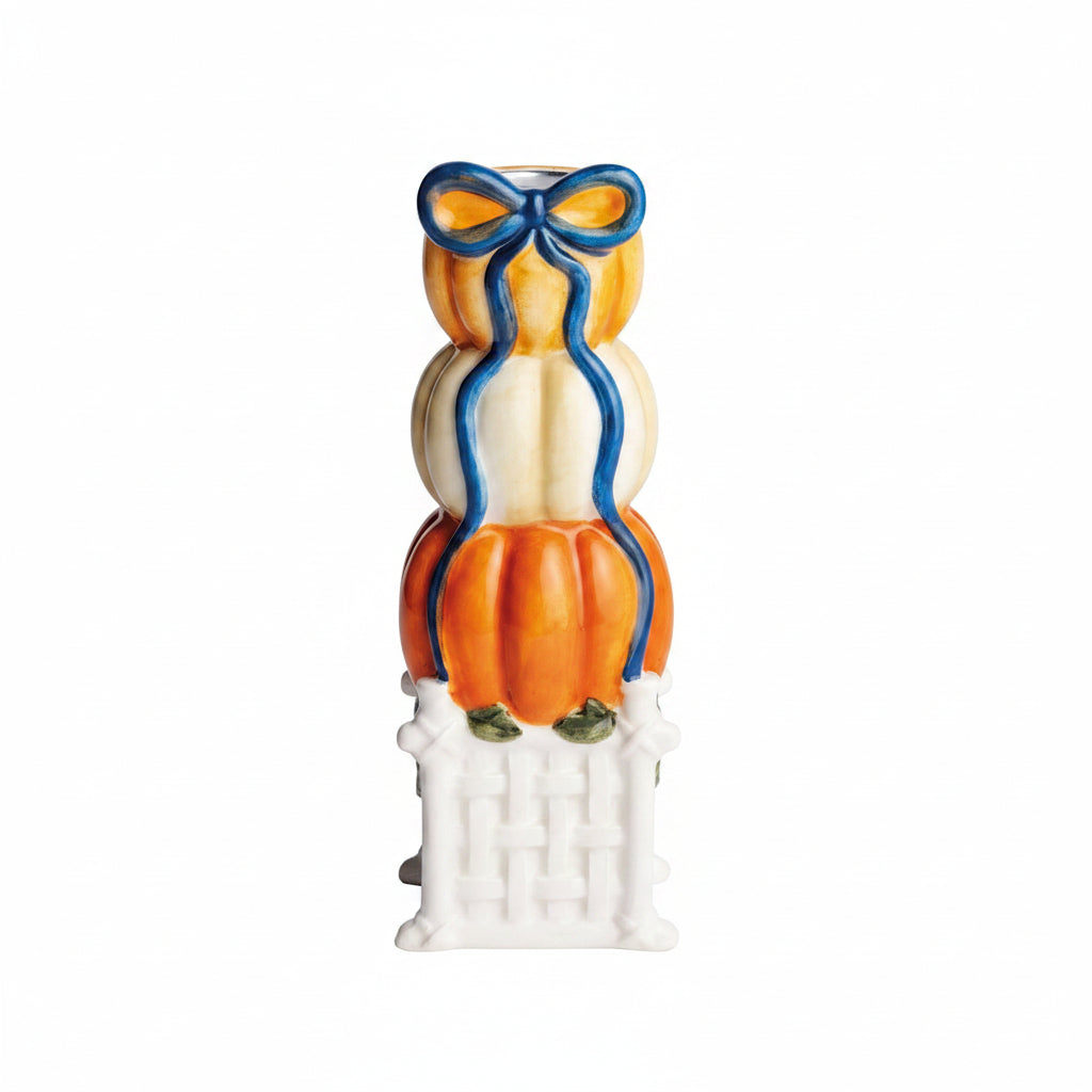 large pumpkin topiary taper holder designed as a stack of three pumpkins, 2 orange, the middle pumpkin is white, white a blue bow painted at top and stack sits on a white pedestal