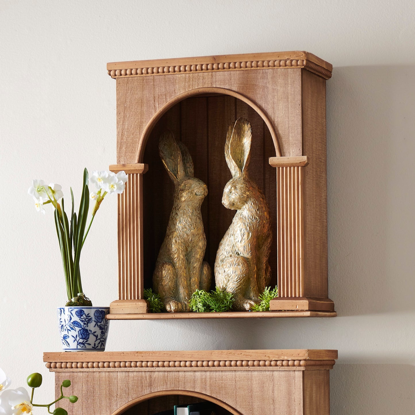 two large gold rabbit figurines in a decorated wood cabinet