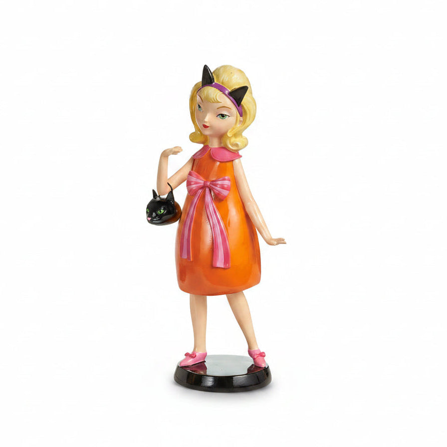 witch figurine wearing an orange dress and pink bow and collar, she has black cat ears on her head and is holding a black cat shape handbag
