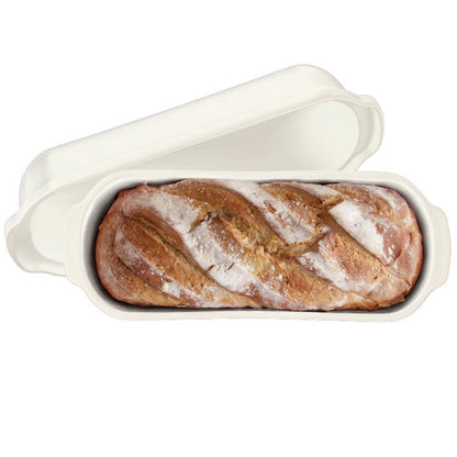 top view of long loaf baker with a baked loaf of bread in it and lid set next to it.