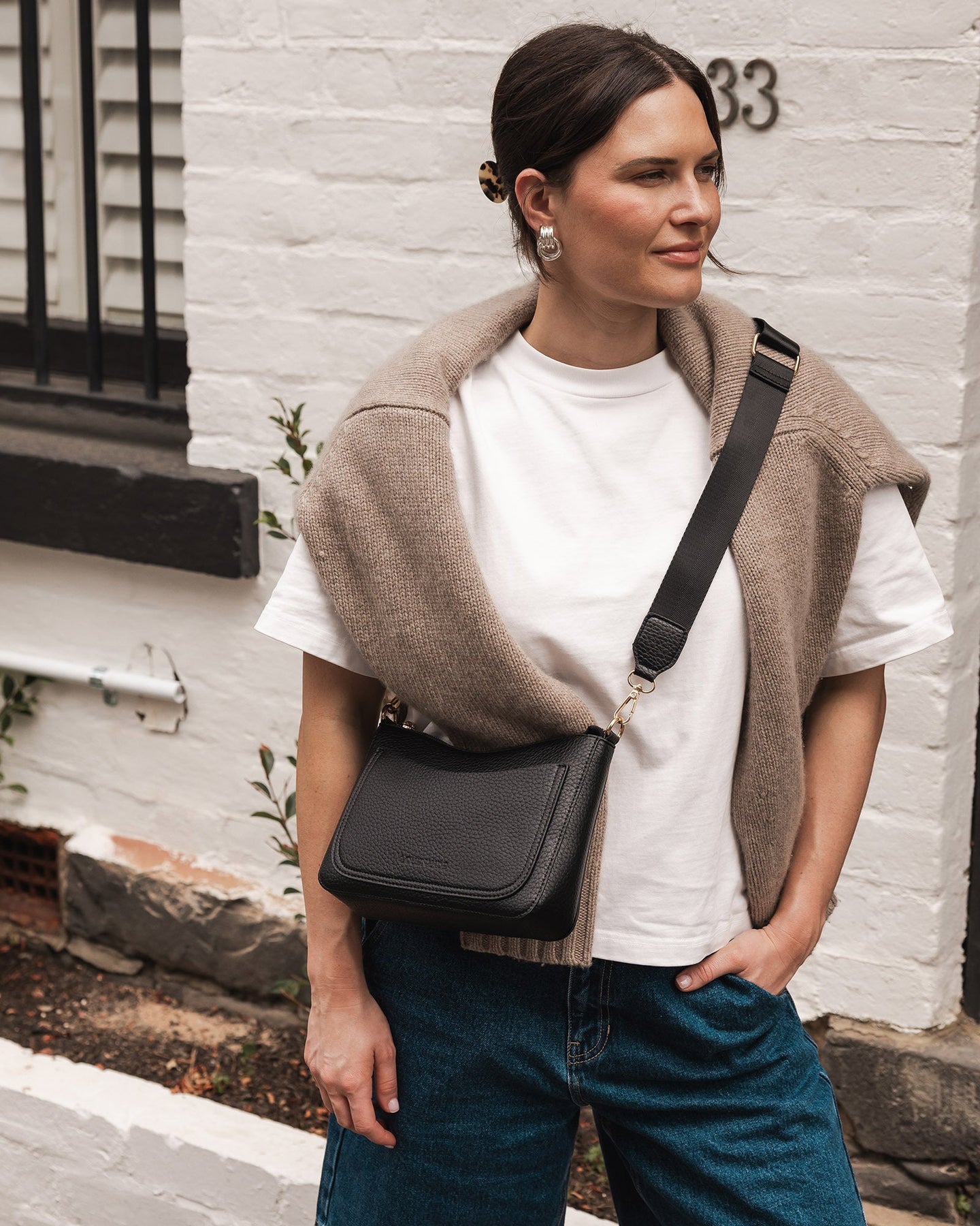 view of person wearing jeans and a tee shirt holding black Linda Crossbody Bag