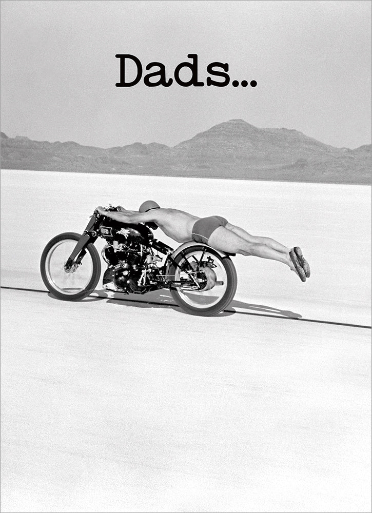 front of card is black and white desert with man laying across a motorcycle with the word dads...