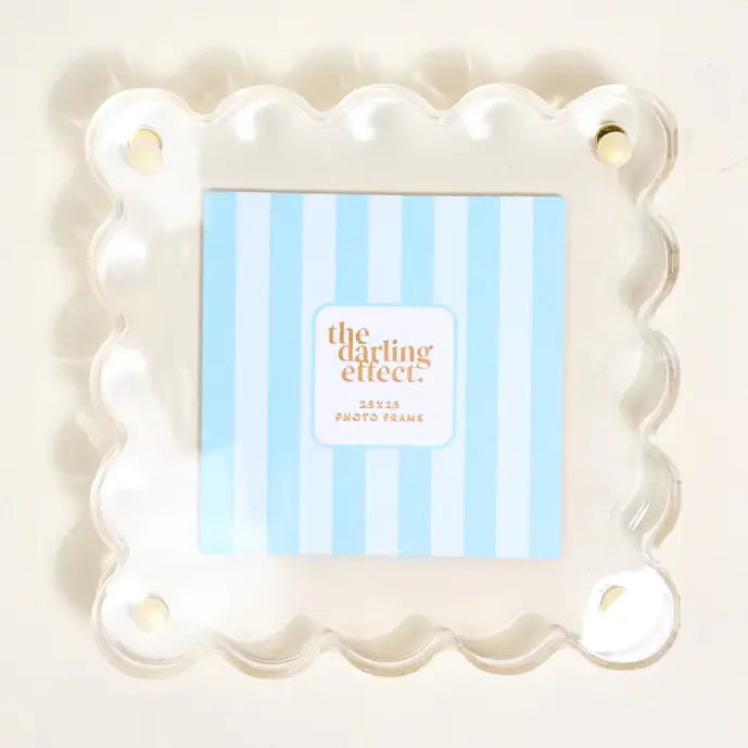 A square clear acrylic photo frame with a scalloped wavy border shown with A blue-and-white striped insert card in it