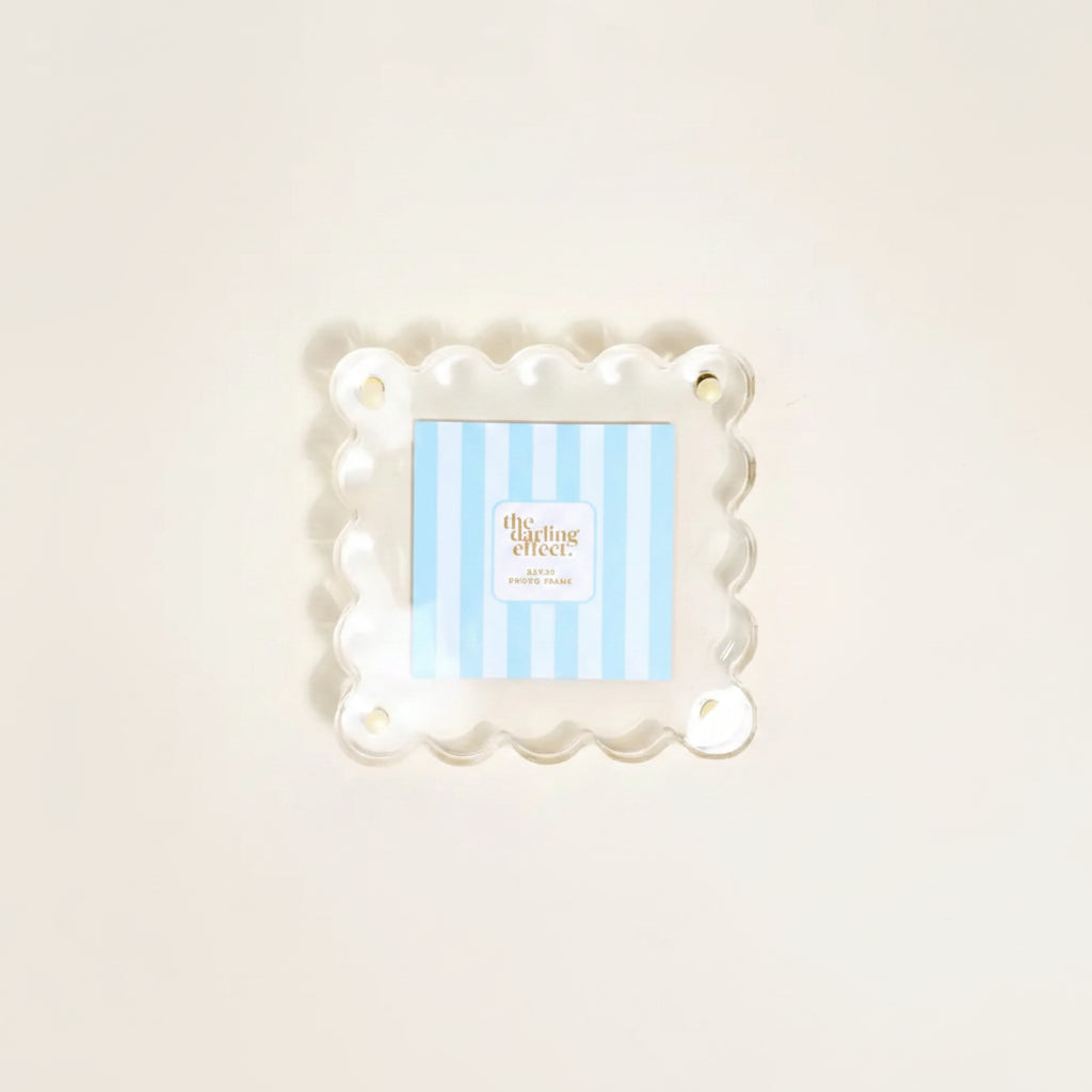A square clear acrylic photo frame with a scalloped wavy border shown with A blue-and-white striped insert card in it