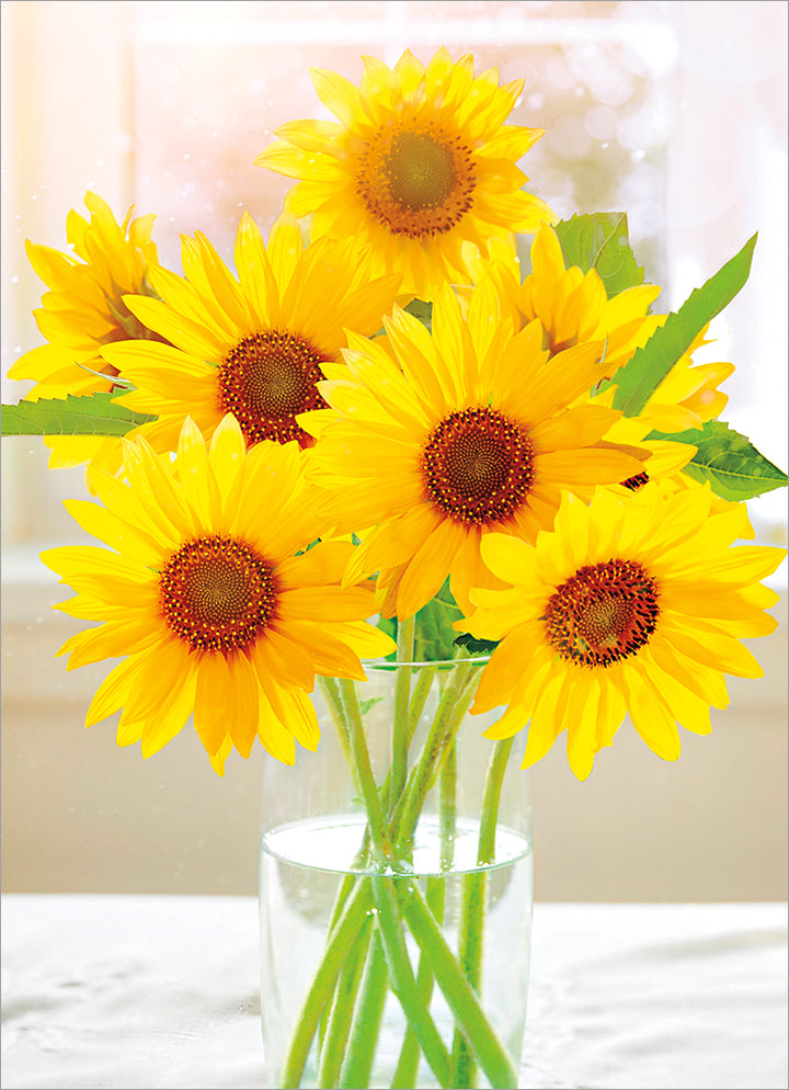 front of card is a clear glass vase with a bouquet of sunflowers