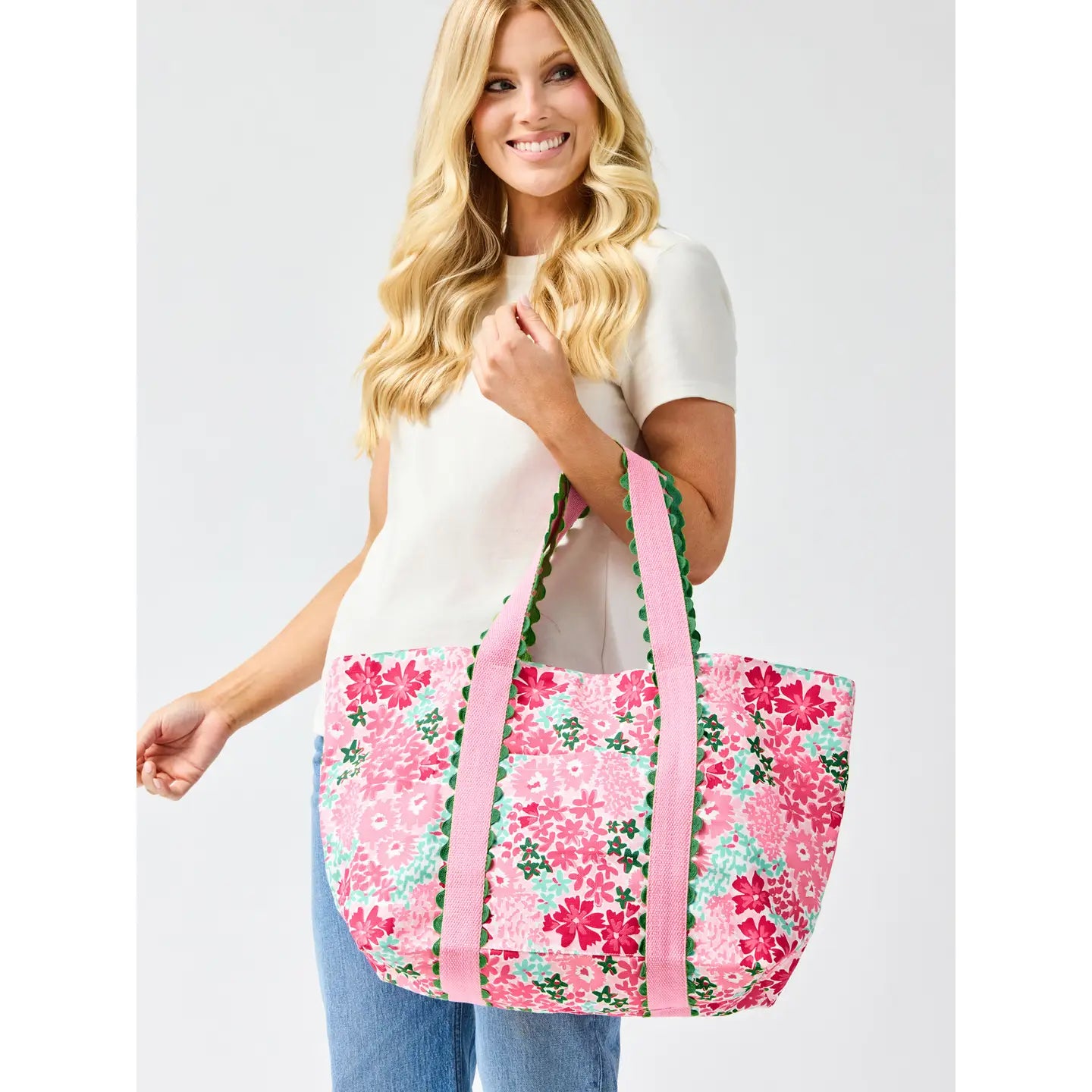 person holding a pink floral tote bag against a white background