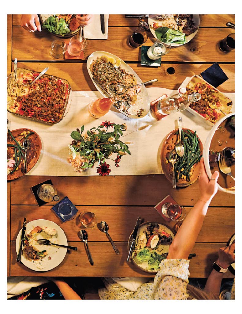 top view of a table set with plates, silverware, glass and assorted hot dishes along the middle.