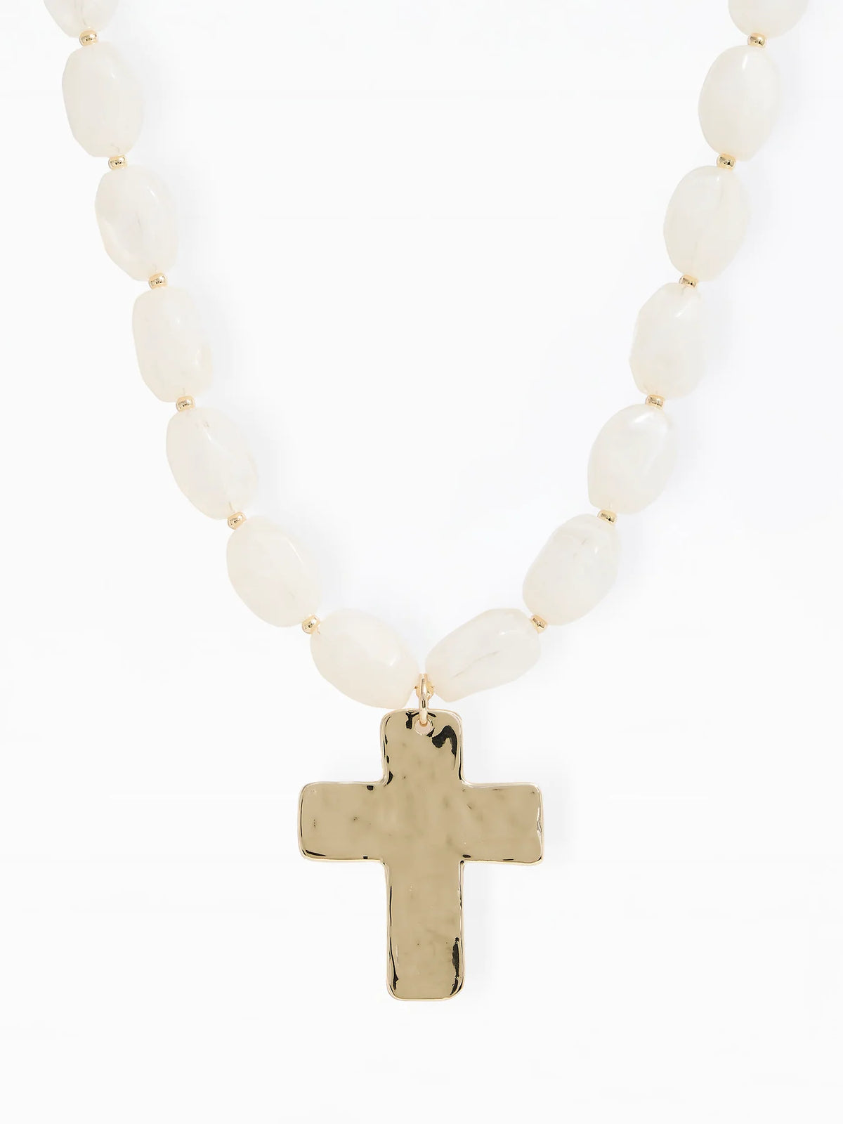 A beaded necklace featuring off-white oval beads and a hammered gold cross pendant, shown against a plain white background.