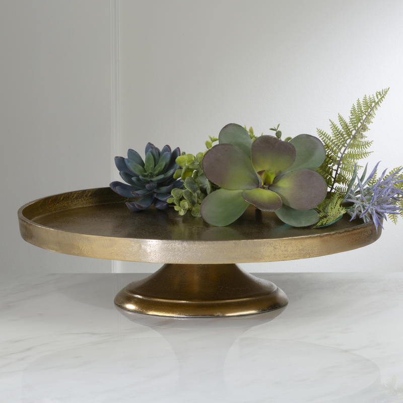 large round gold pedestal with greenery on it
