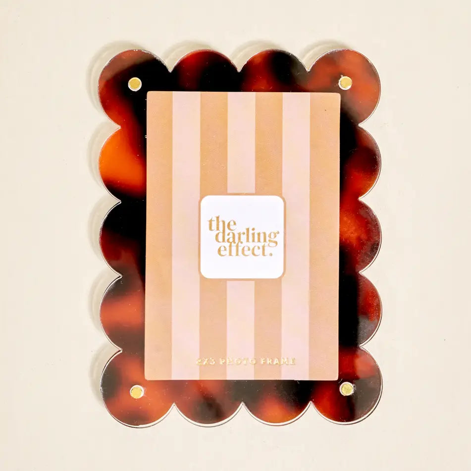 Decorative photo frame with tortoiseshell design and 'the darling effect' branding insert card shown on a beige background