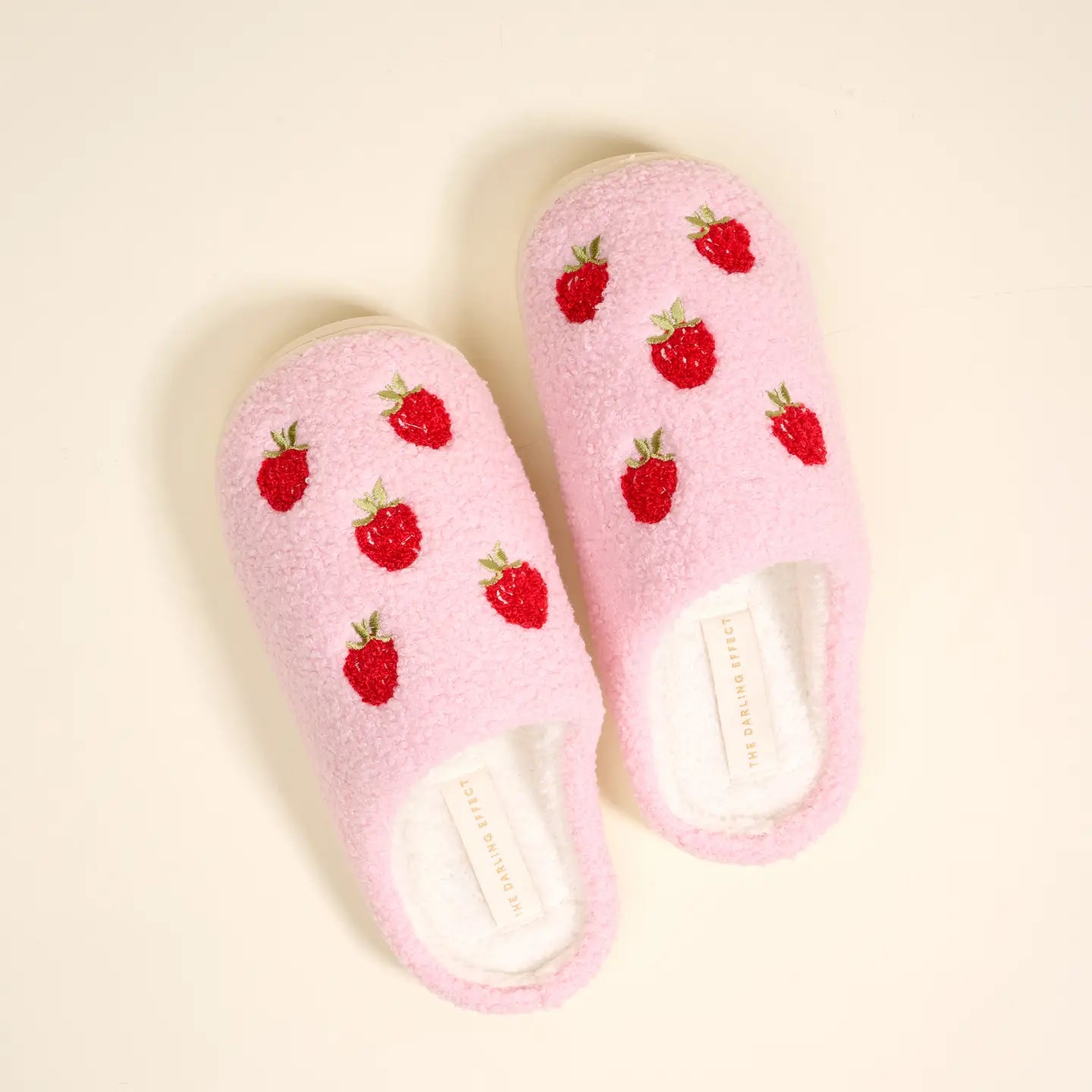 Pink slippers with red strawberry pattern on a beige background