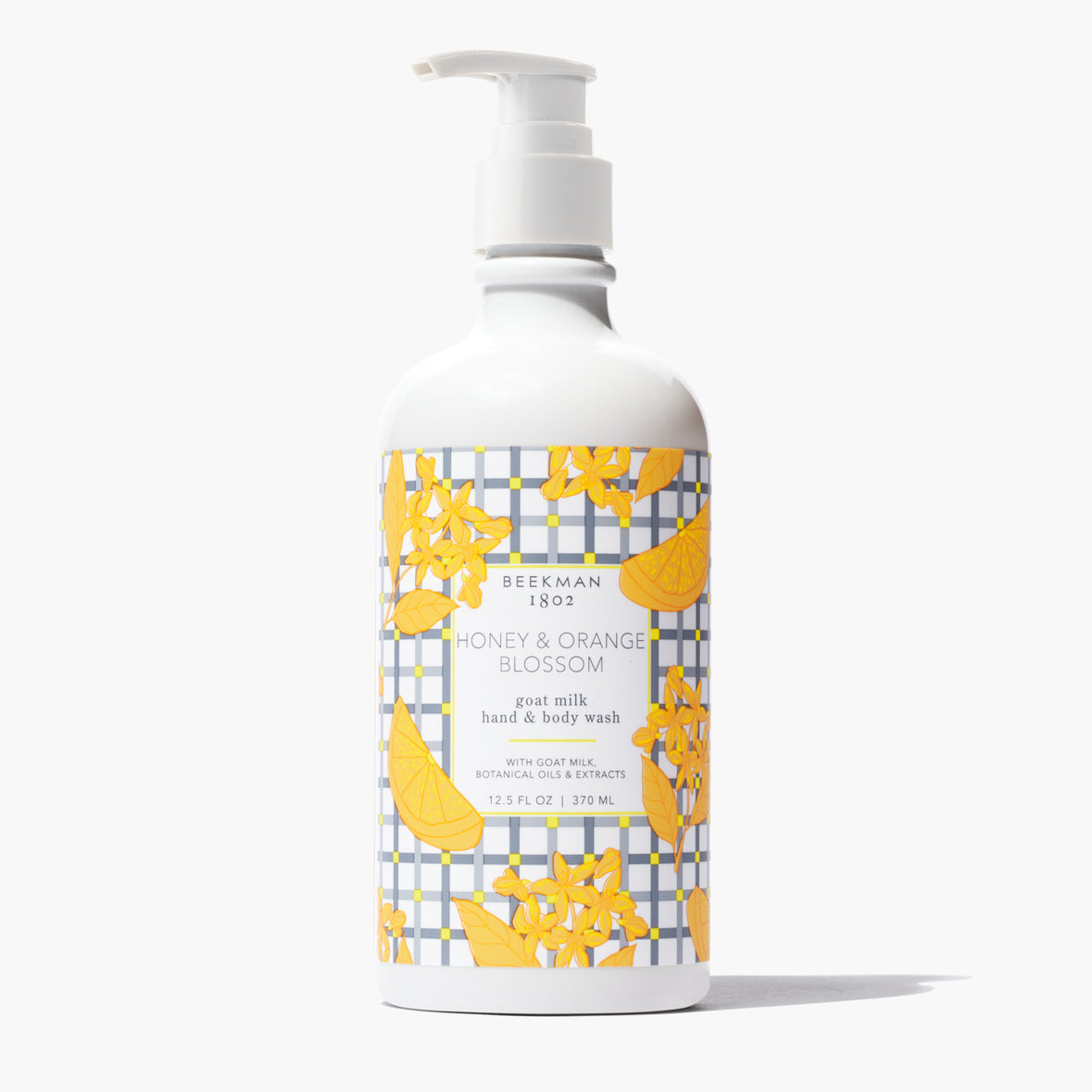 white pump bottle of Honey & Orange Blossom Hand & Body Wash with an orange blossom and grey grid printed label