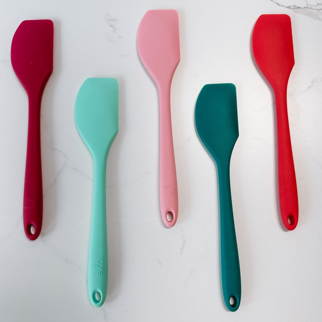 5 colors of mini pointed spatulas arranged on a marble background.
