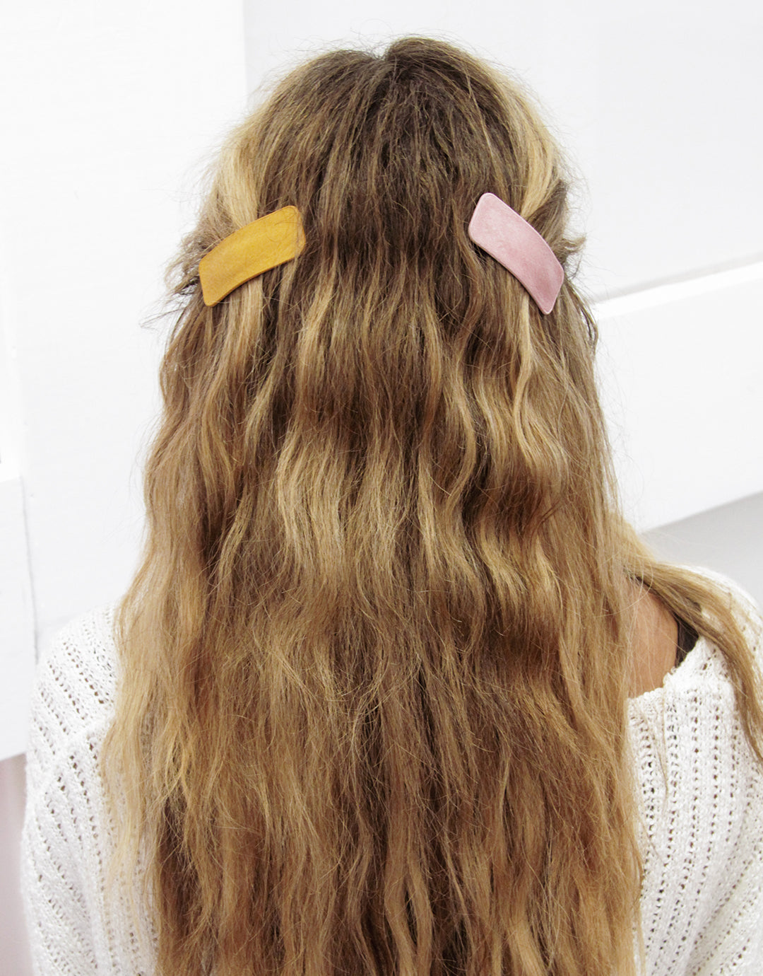 back view of person with long wavy blonde hair clipped on each side with barrettes.