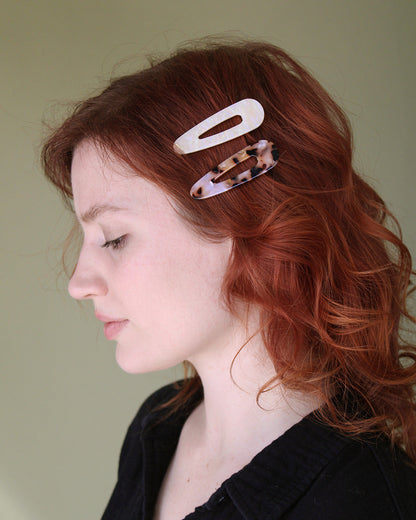 person with red curly hair with 2 clips on one side.