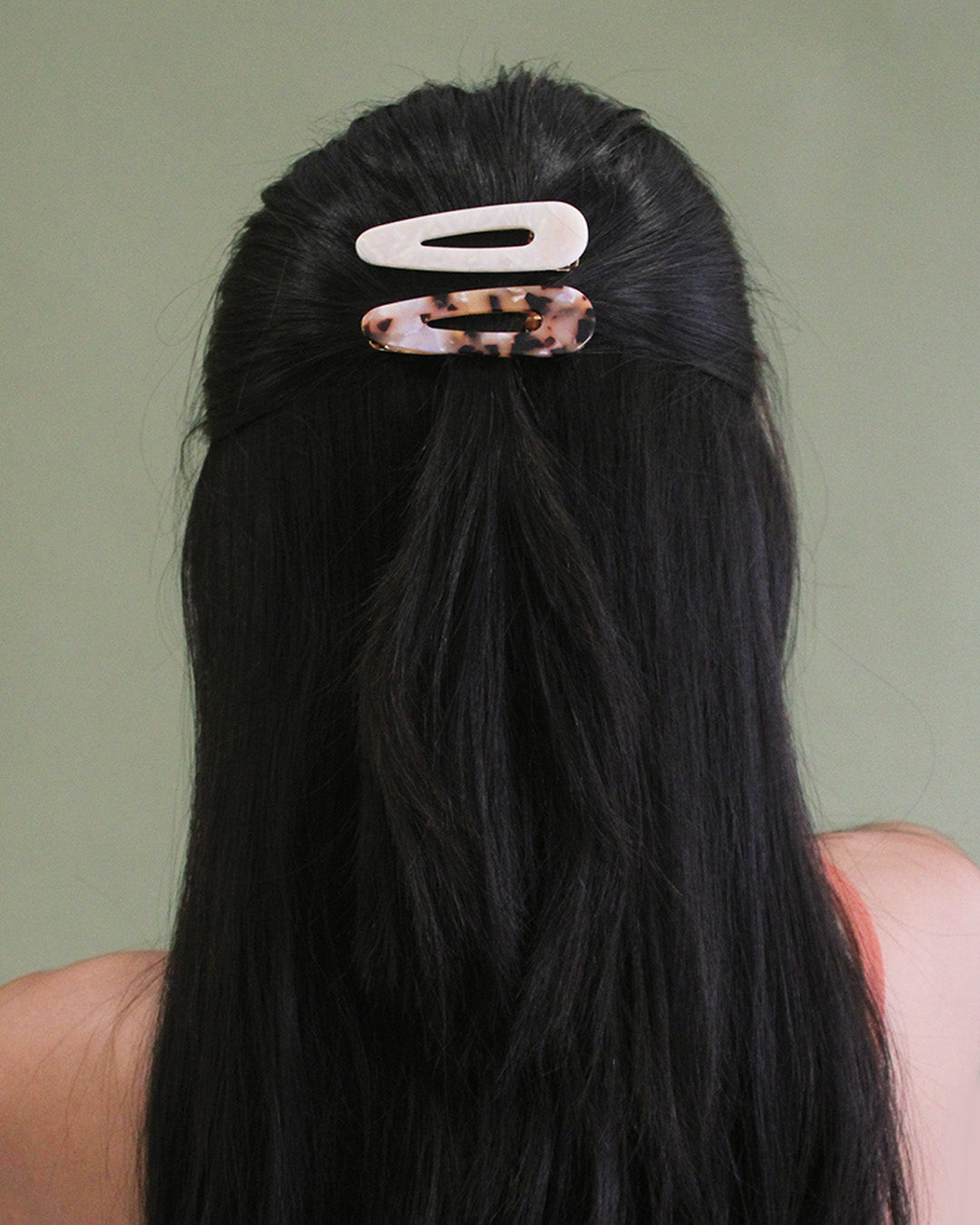 person with black straight hair with half of it pulled back and clipped with 2 clips.