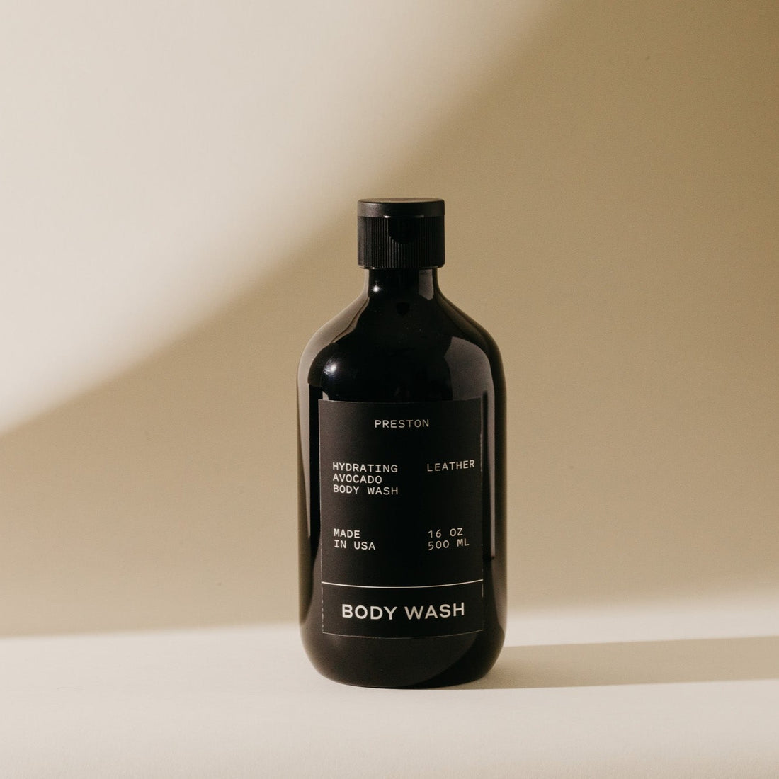 Black body wash bottle with label on a beige background