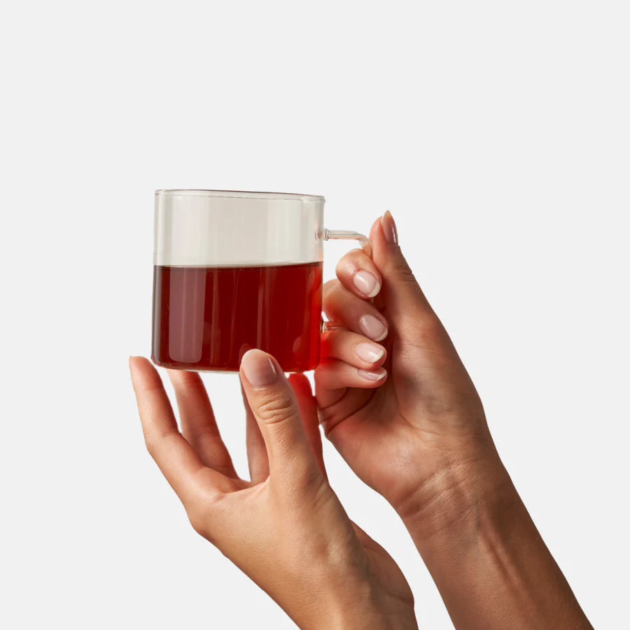 hand holding glass mug filled with blushing tea