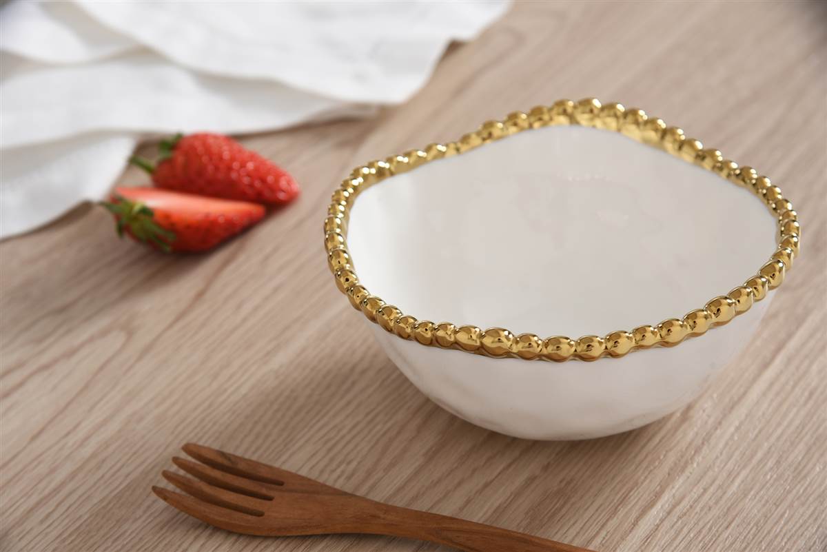 white and gold snack bowl on a wooden table with strawberries in the background
