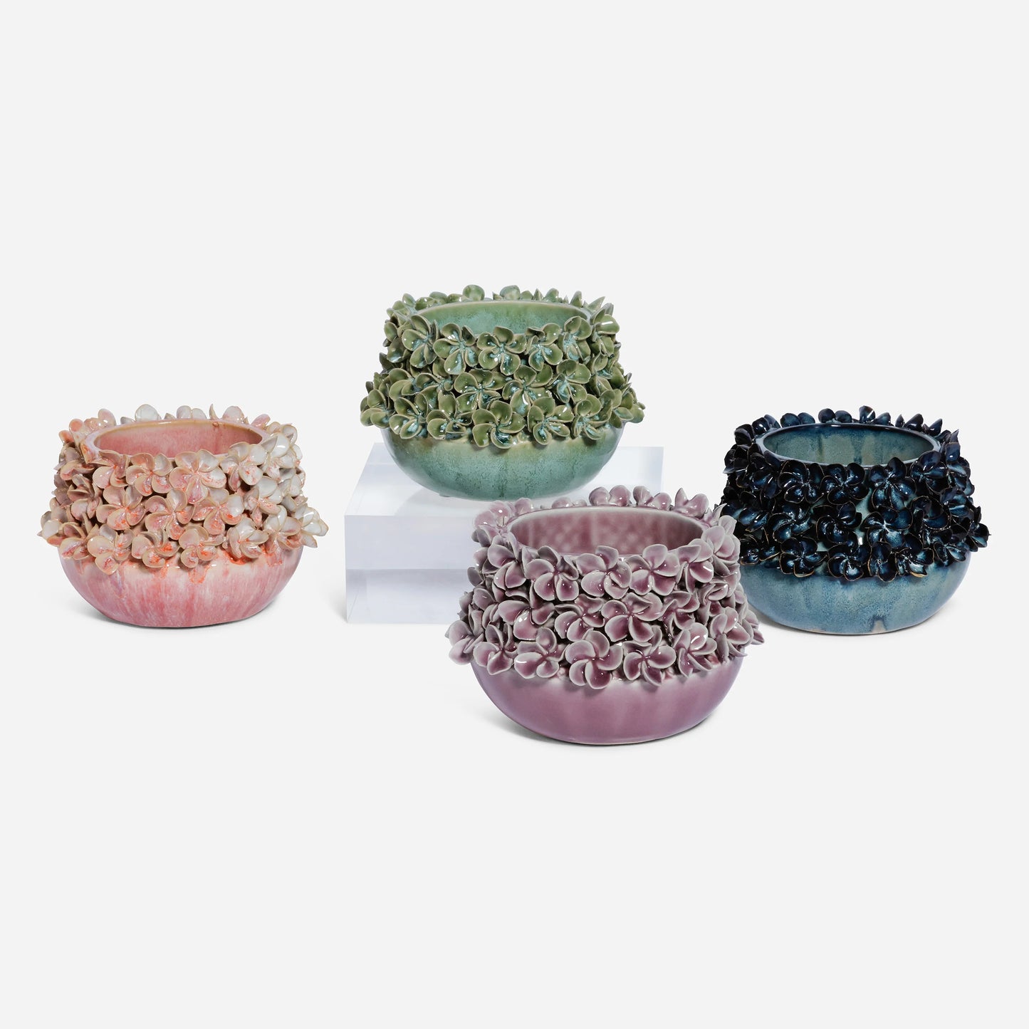 Four ceramic planters with textured floral surfaces on a white background