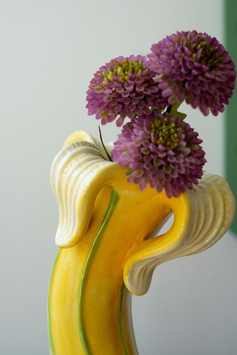 close-up of Banana Vase with purple flowers in it