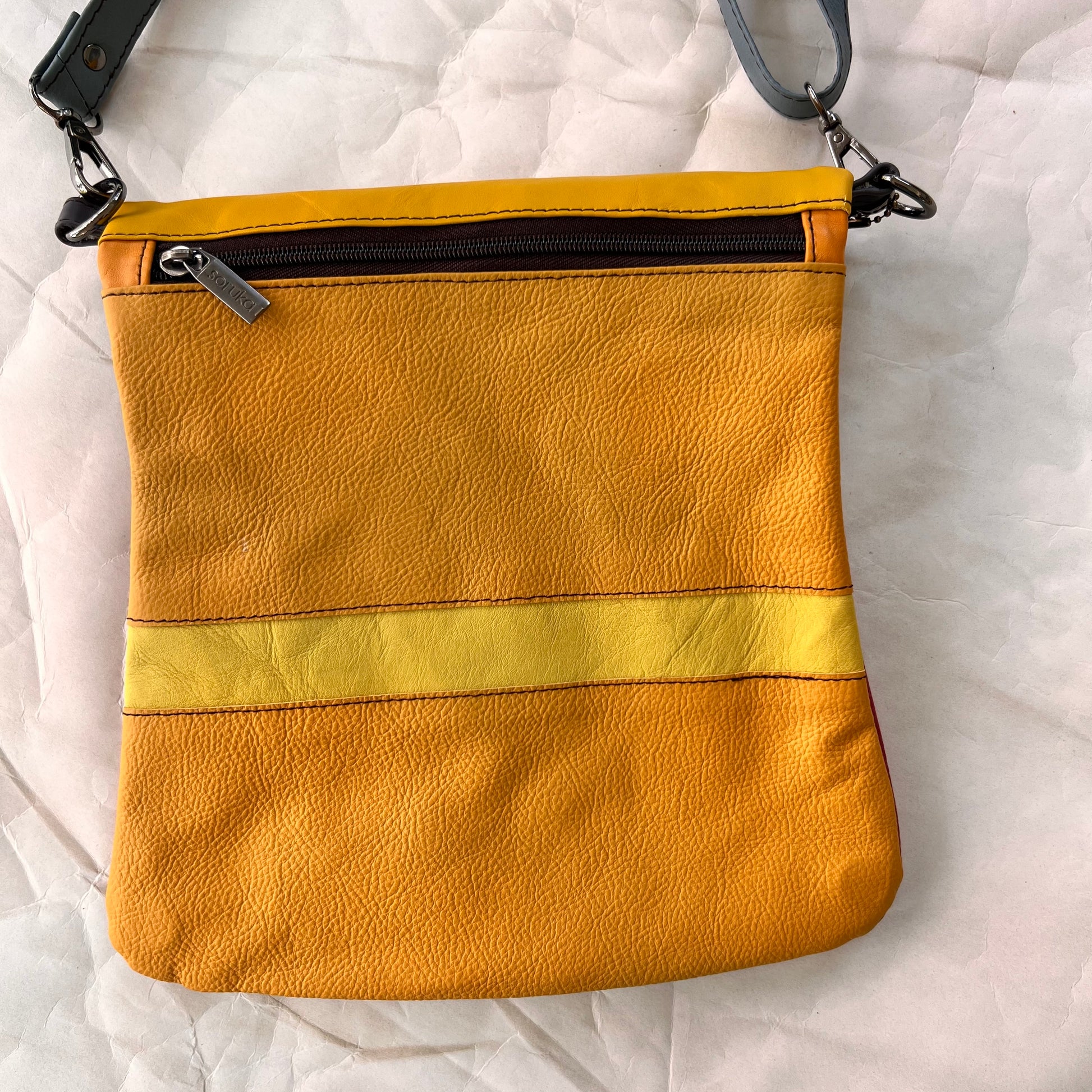 shades of yellow striped greta bag with zipper across the top.