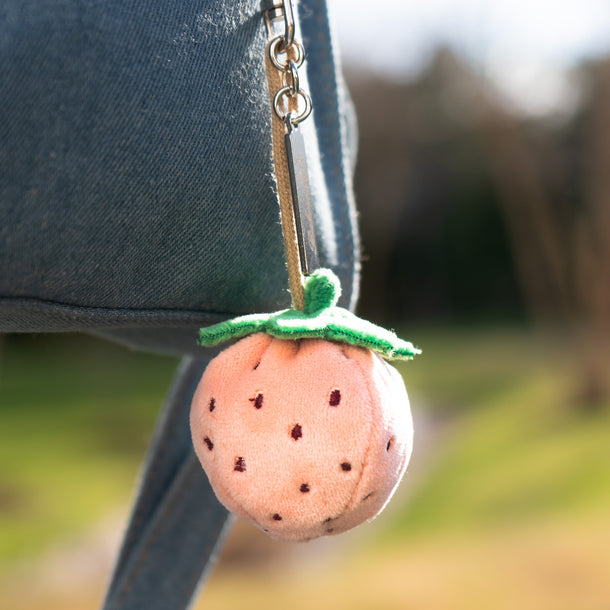 Pink Strawberry bag charm slipped to a denim bag