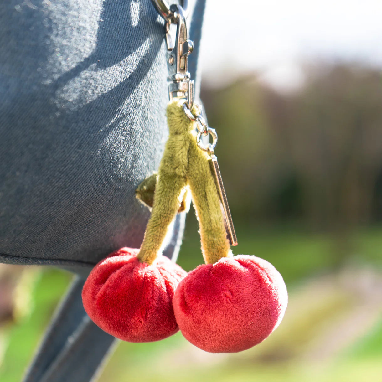 cherry bag charm clipped on a denim bag