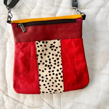 red greta bag with animal print block in the center with maroon stripe and zipper across the top.