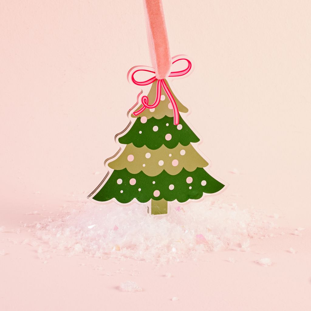 flat dark and light green acrylic ornament shaped like a treed shown on a pink background