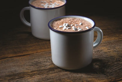 mugs filled with campfire hot chocolate set on a wooden table.