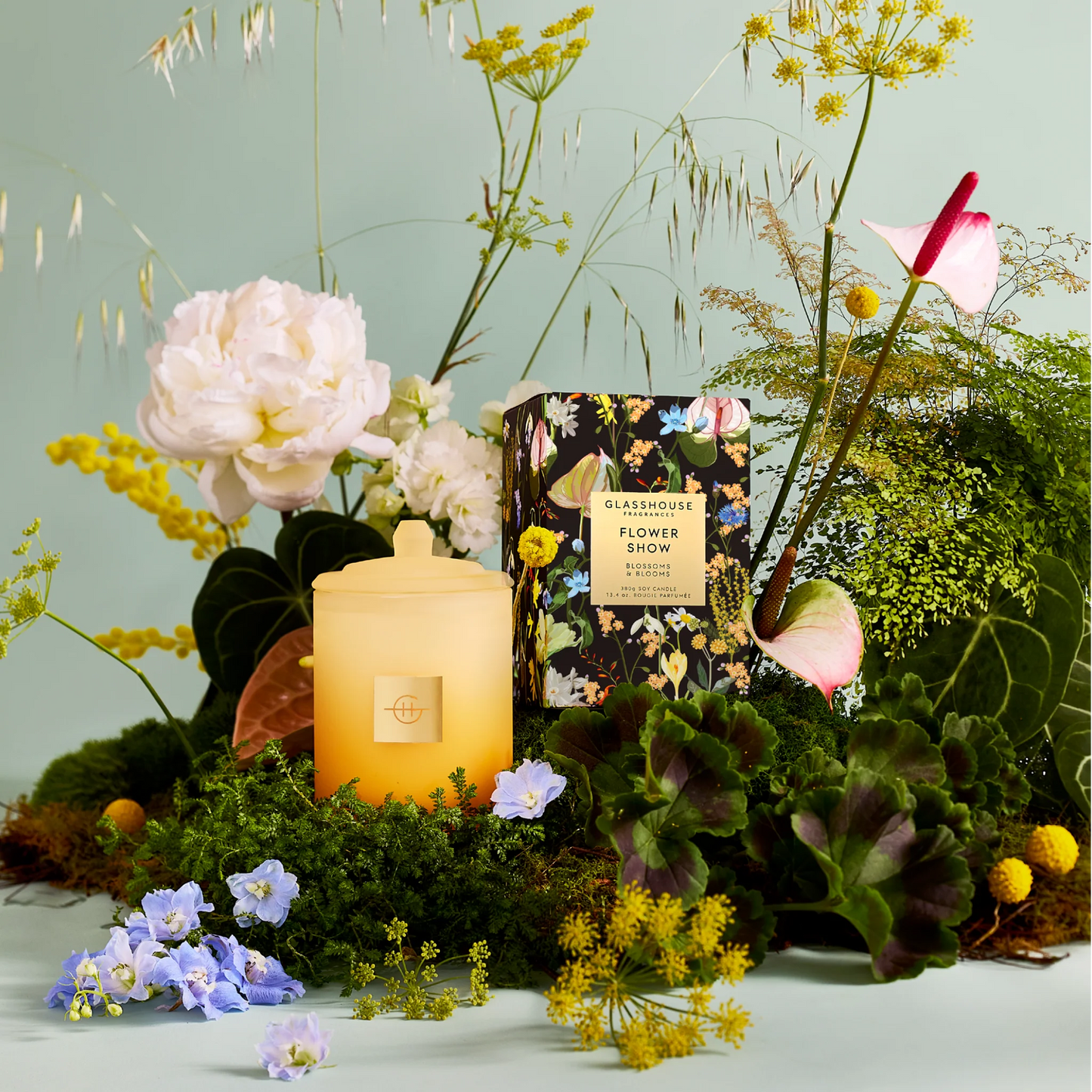 flower show Candle with a floral arrangement on a light green background