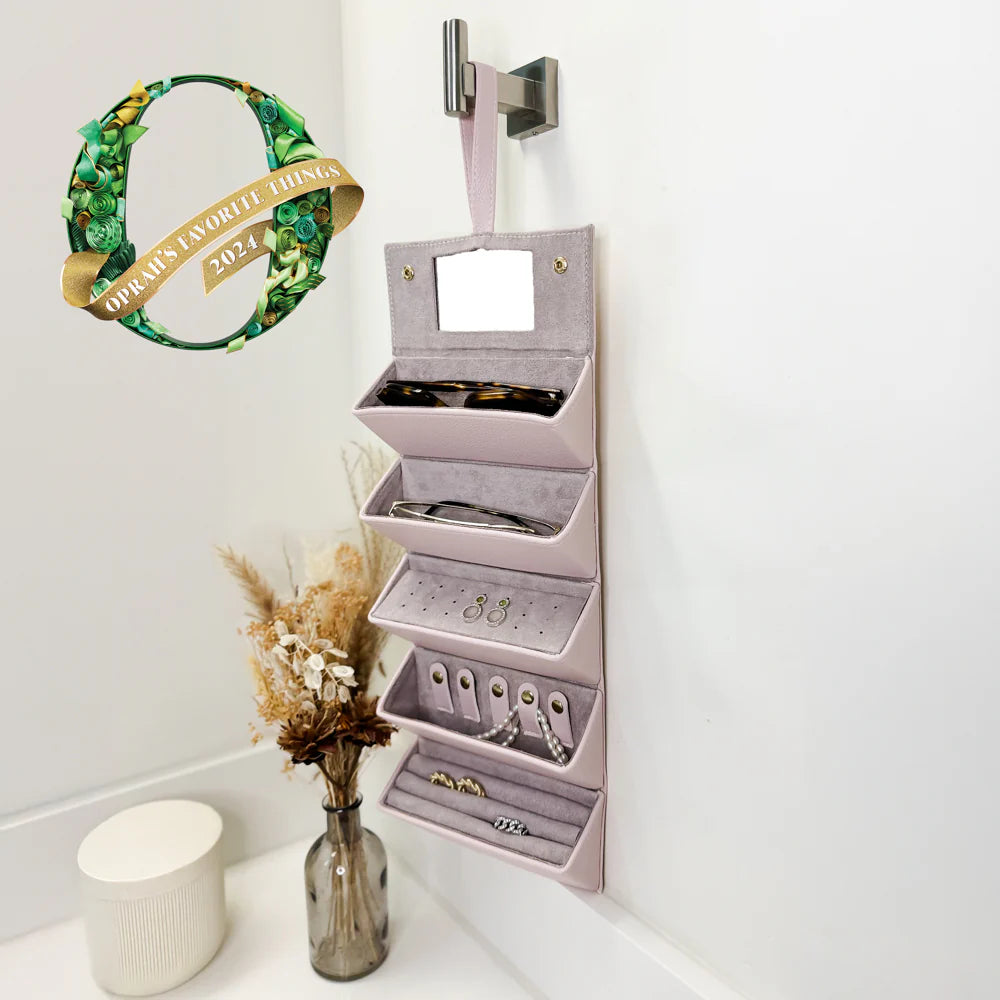 pink jewelry case hung on wall and filled with glasses and jewlery