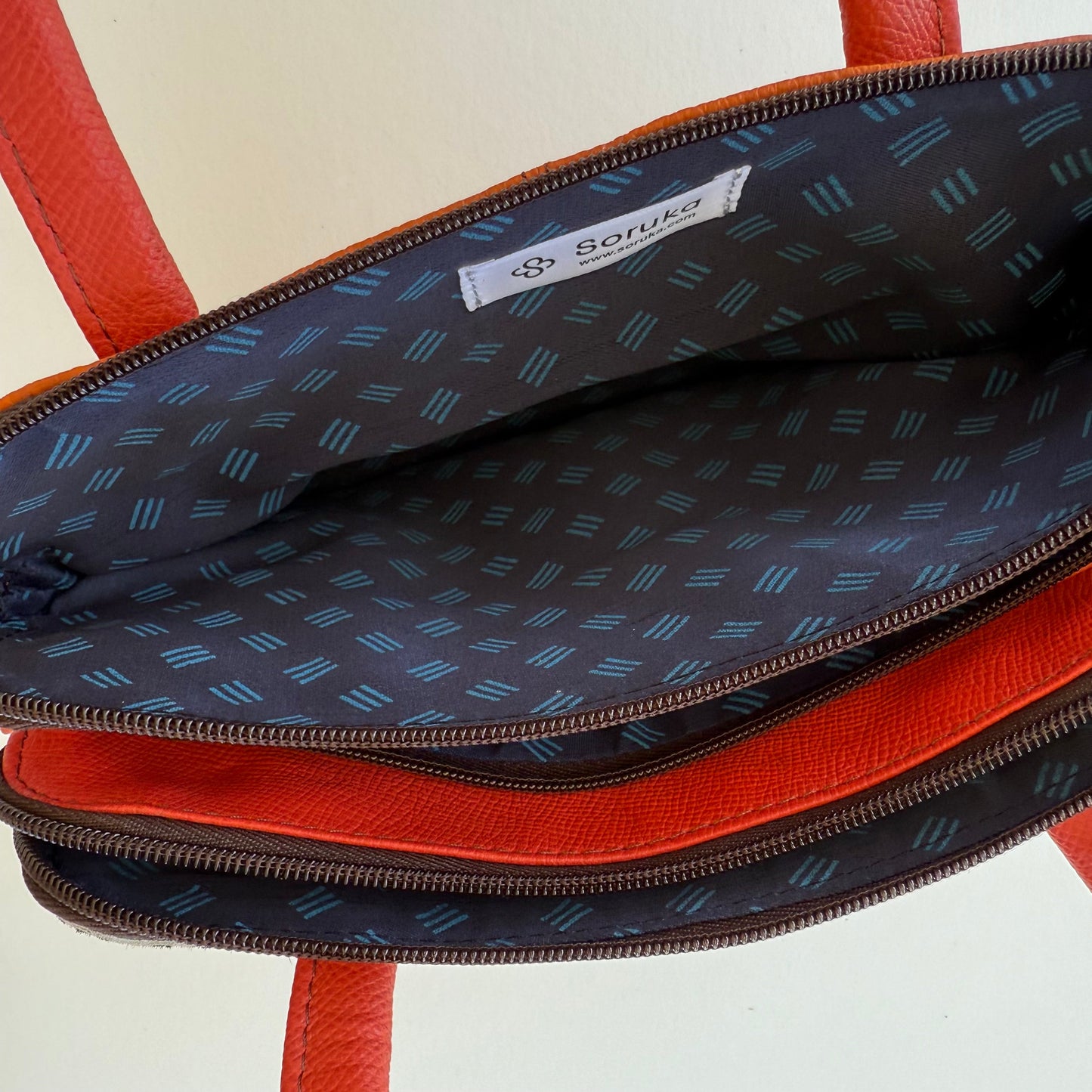 top view of orange handbag showing blue patterned interior lining