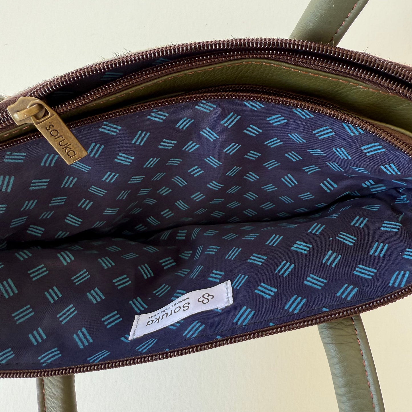 top view of green leather handbag showing blue patterned interior lining