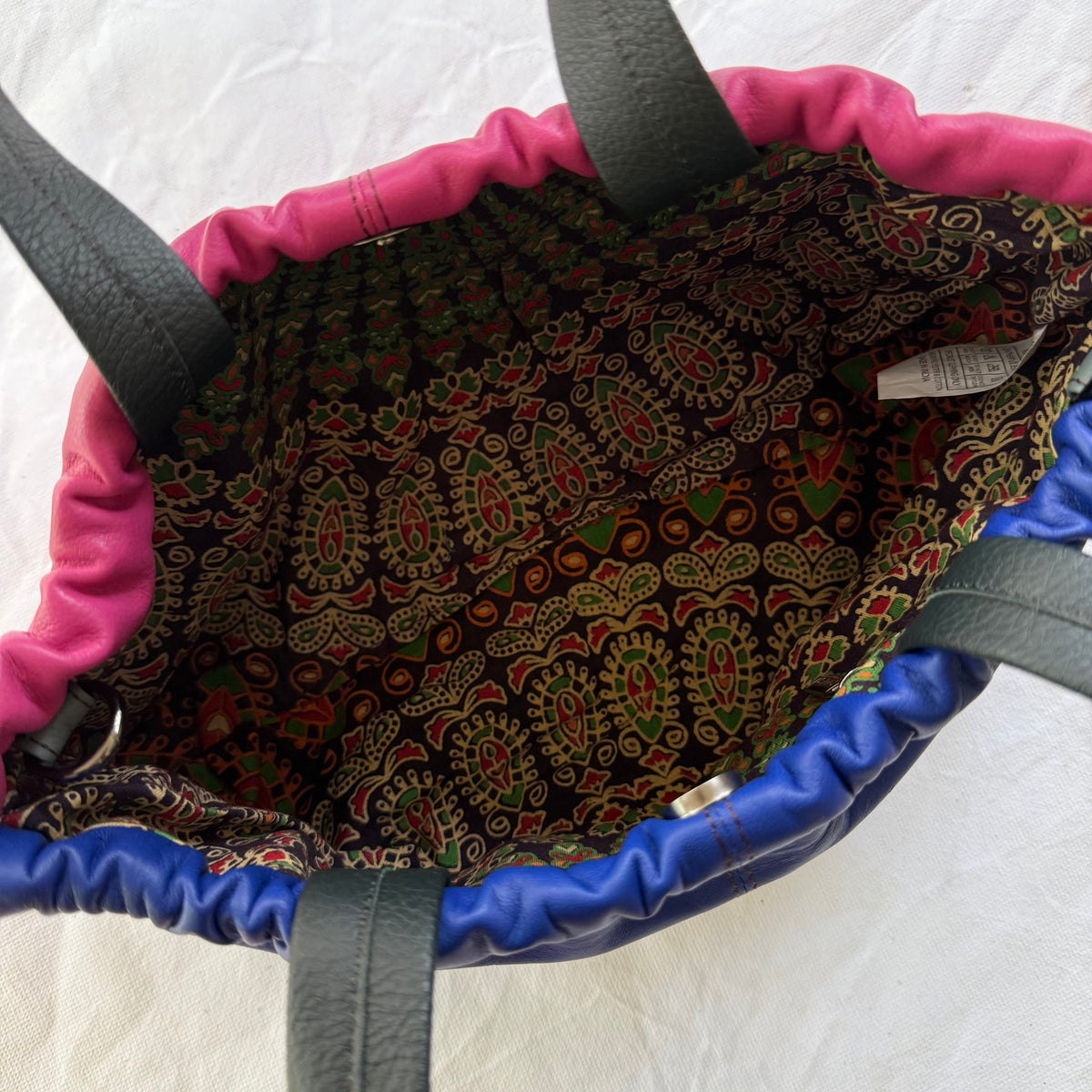 interior view of handbag showing pattern lining, zip pocket, and magnetic snap closure