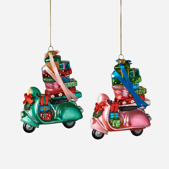 Two holiday ornaments shaped like scooters, one green and one pink, each loaded with wrapped gifts and bows.