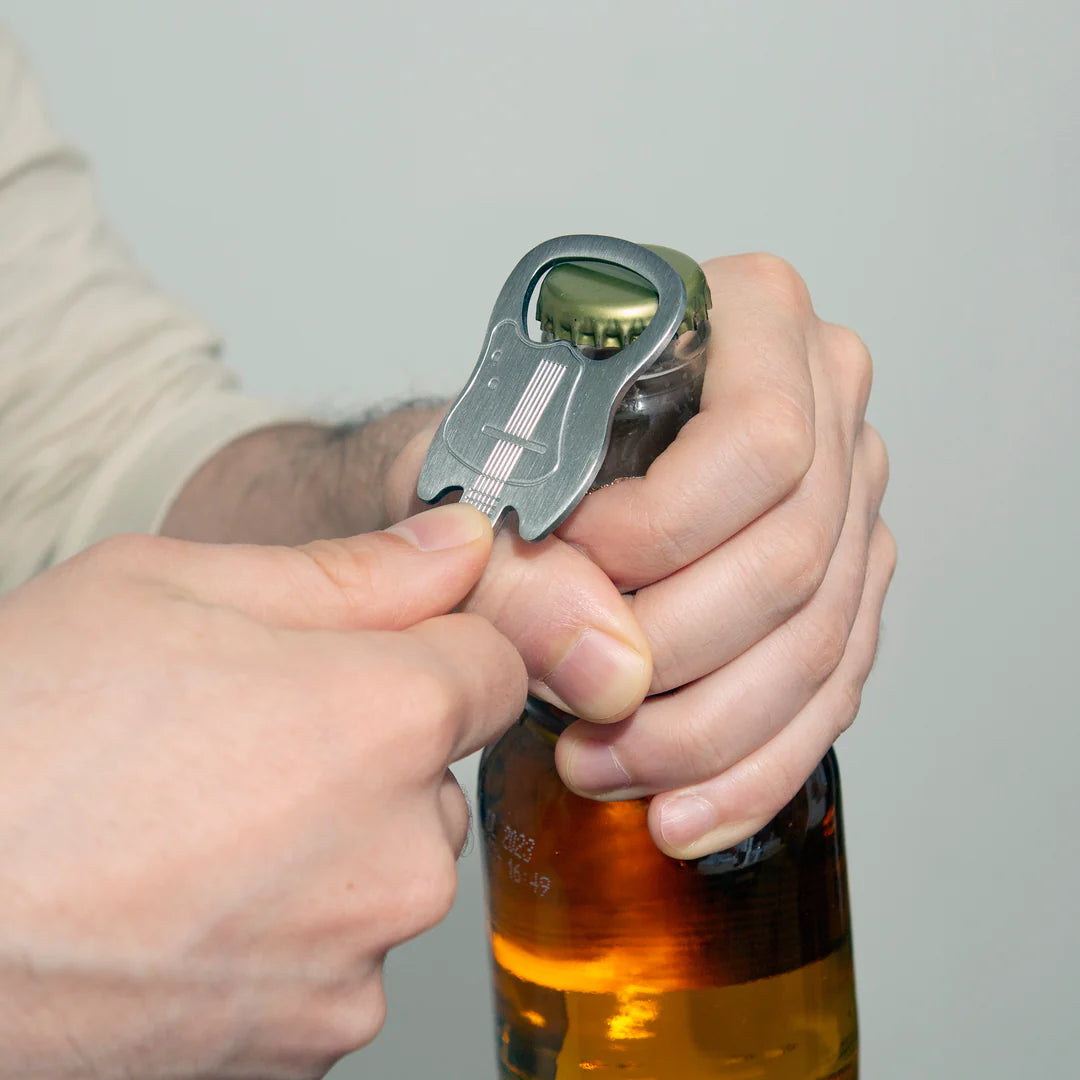 hands using guitar bottle opener to open a bottle.