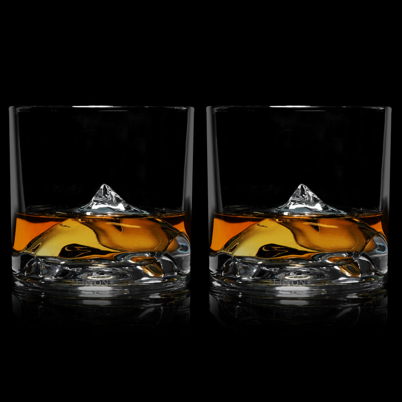 Everest Crystal Whiskey Glasses partially filled with whiskey on a black background.