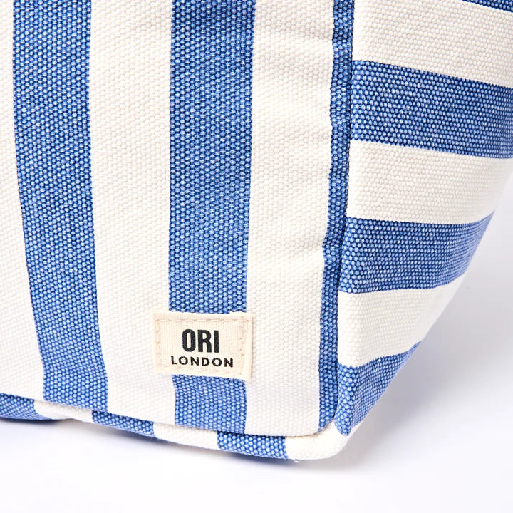 close-up of corner of Blue and white striped tote bag with 'ORI London' label on a white background