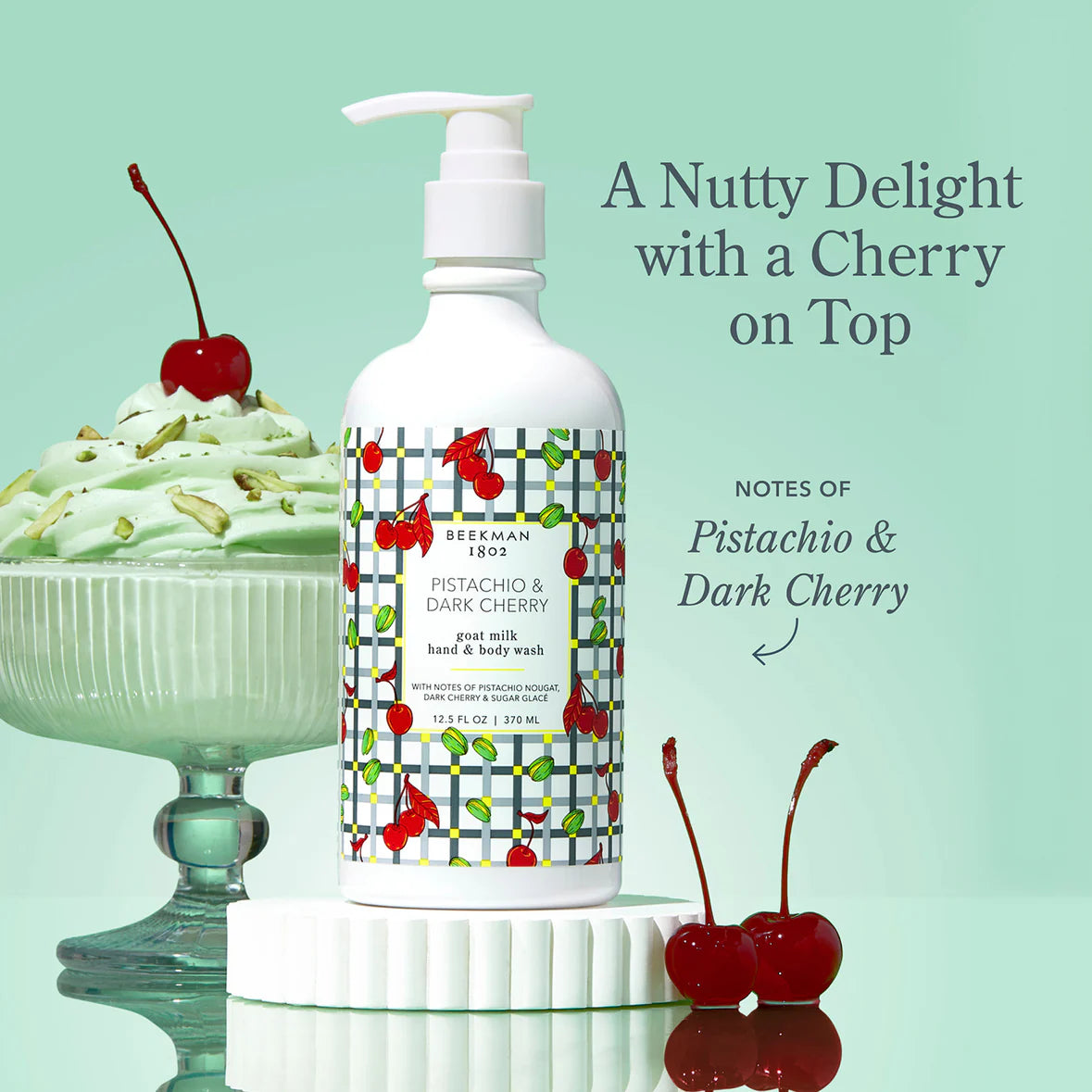 Hand and body wash bottle with cherry design next to a Pistachio dessert and cherries on a light green background